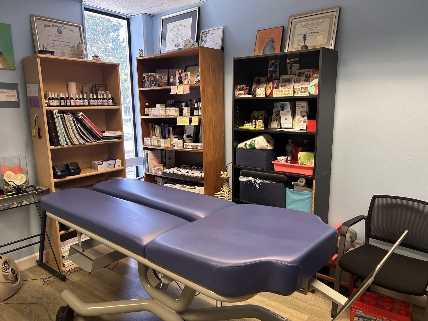 The Sunnyvale treatment room: the adjusting table, shelves of supplements and books, and framed diplomas on the wall. No one is in the room.